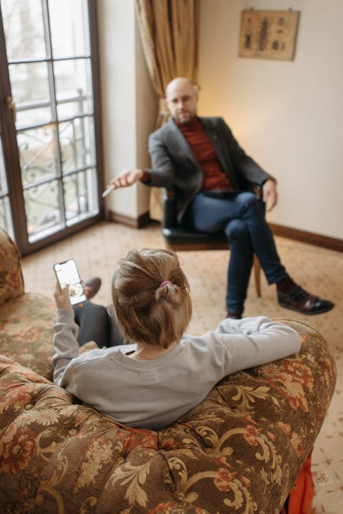 Free A Man Sitting in Front of a Woman Using Her Cellphone Stock Photo