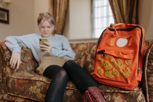 A Girl Sitting on Couch Beside an Orange Bag