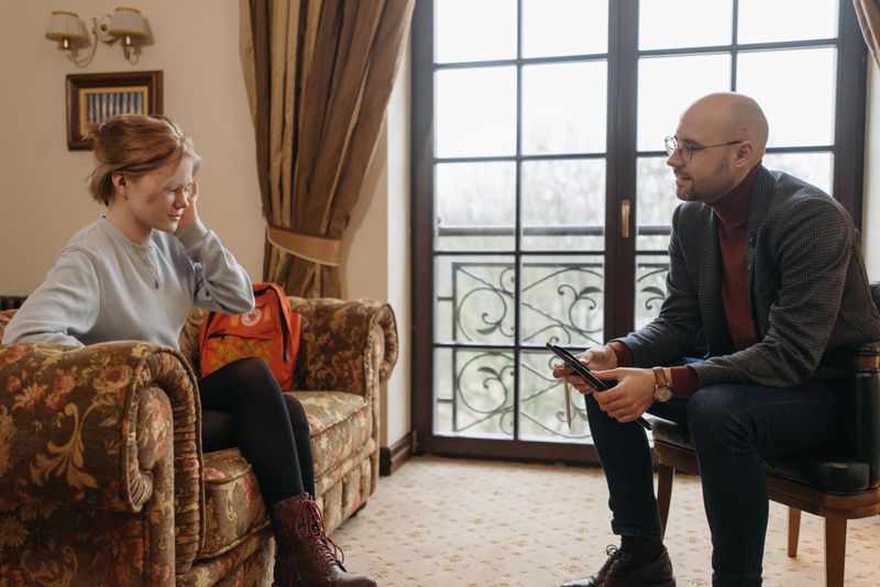 A counselor and client engage in conversation during a therapy session in a cozy room