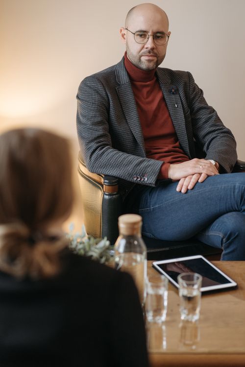 Free Two adults having a focused discussion in an office setting with a tablet on the table. Stock Photo
