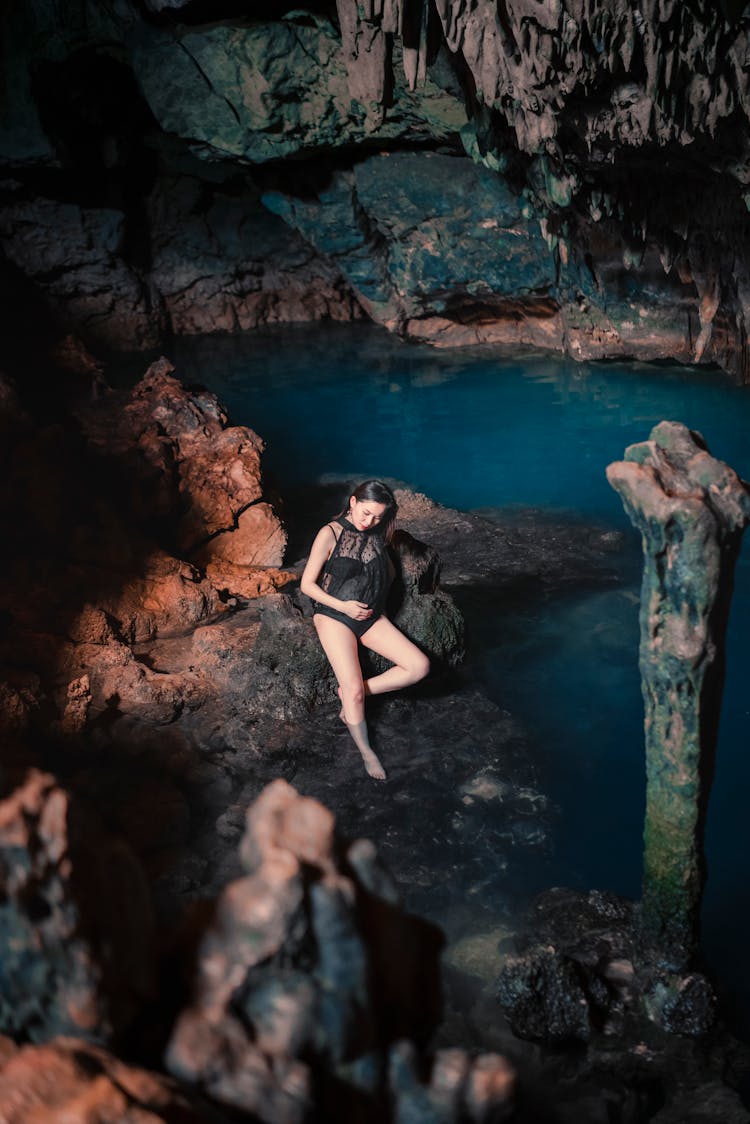 Woman Sliding Into Water Pool Inside Cave