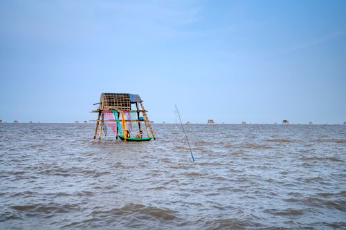Free Workers in boat near typical structure for raising clams installed in sea water in Vietnam Stock Photo