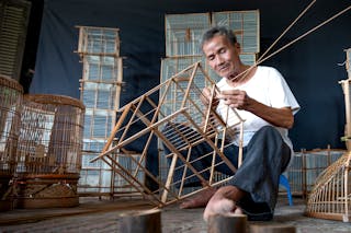 Senior concentrated Asian man creating bird cages