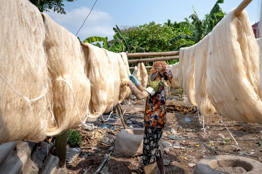 Asian woman checking drying silk threads