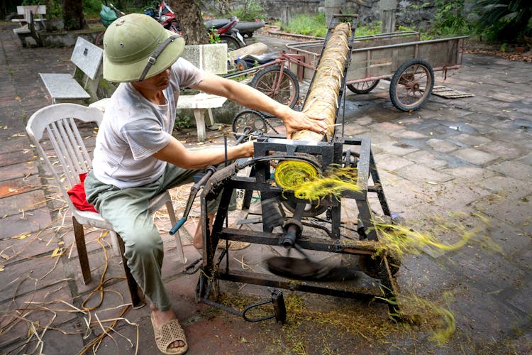 Unrecognizable Ethnic Worker Cutting Tobacco On Roll Press Machine