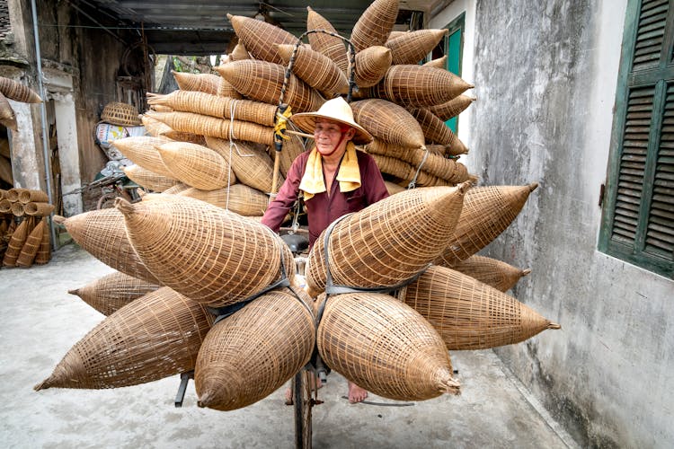 Senior Vietnamese Man Riding Bicycle With Bamboo Fish Traps