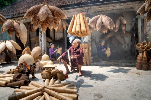 Free Senior ethnic women making wooden wicker traditional fish traps in shabby gray yard of house Stock Photo