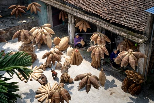 Free From above of people sitting and making bamboo fish traps while working on local bazaar in Vietnam in daylight Stock Photo