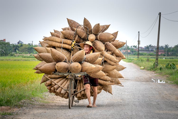 Asian Man Carrying Bamboo Fish Traps In Countryside