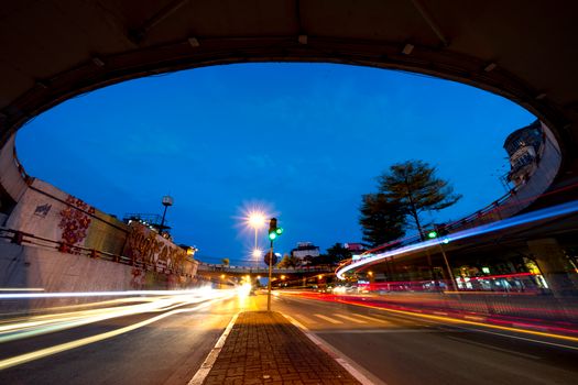 Picturesque cityscape with bright traffic over asphalt roadway placed in city in night time