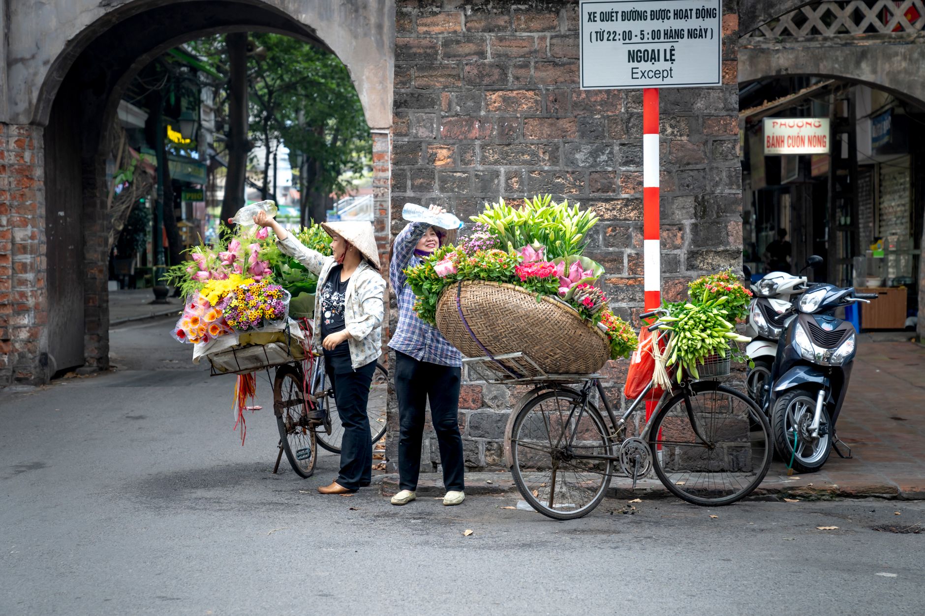 Vendedores ambulantes vendiendo flores de colores en bicicleta en un entorno urbano.