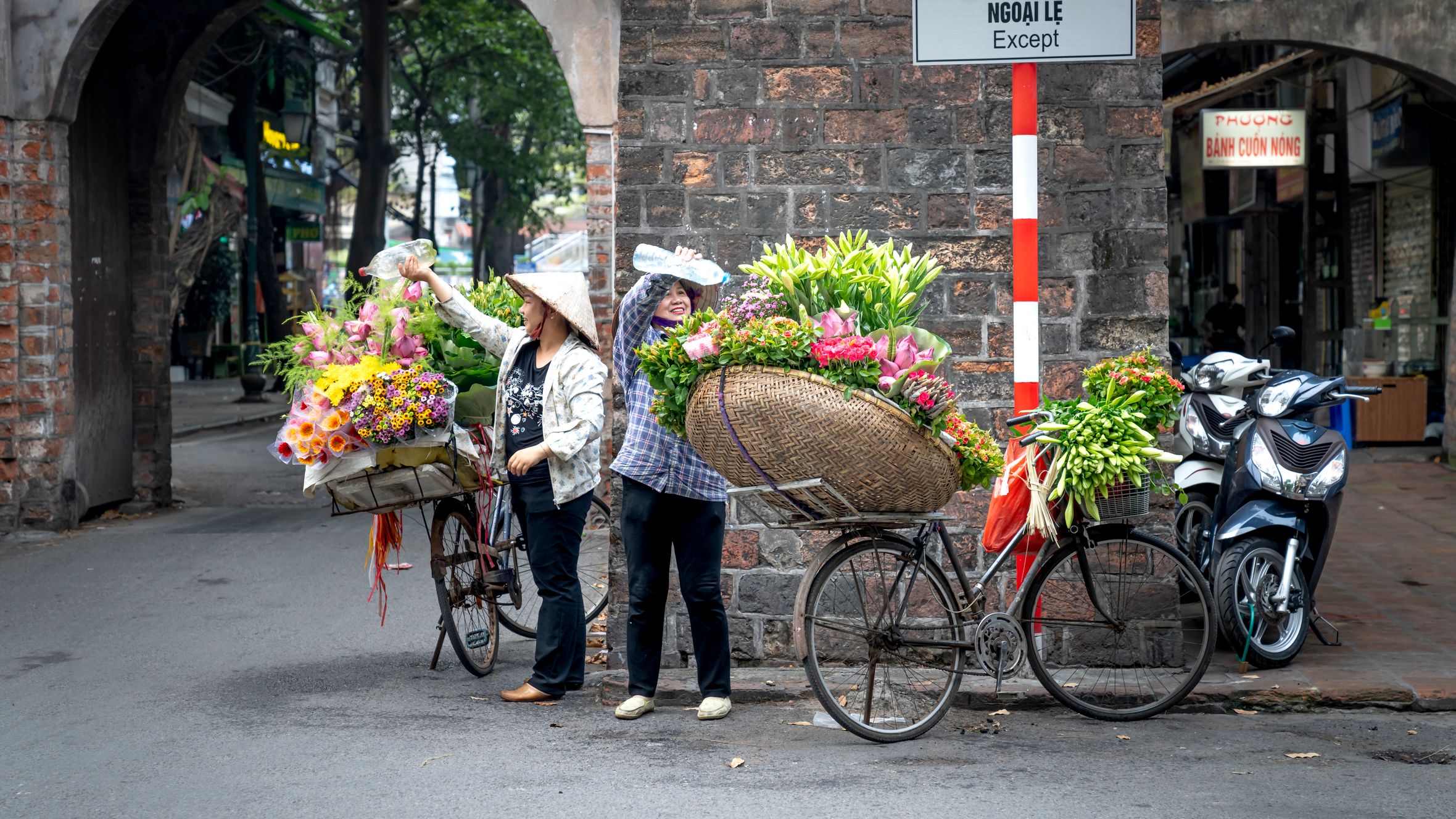 Street vendors selling colorful flowers on bicycles in an urban setting.