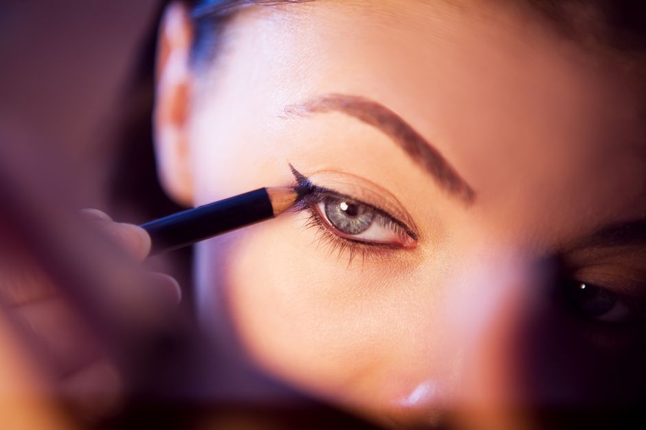 A close-up shot of a woman applying eyeliner with precision.