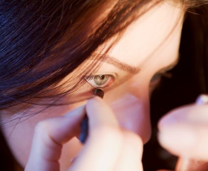 Close-up view of a woman precisely applying eyeliner with focus.