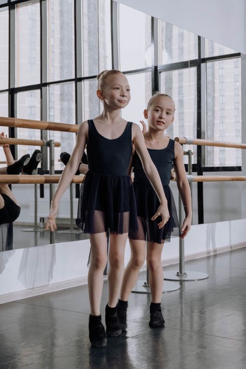 Free A pair of young ballerinas practicing ballet in a bright dance studio with mirrors. Stock Photo