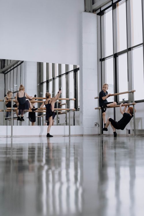 Free Young dancers stretching at a ballet barre in a sunlit studio. Stock Photo