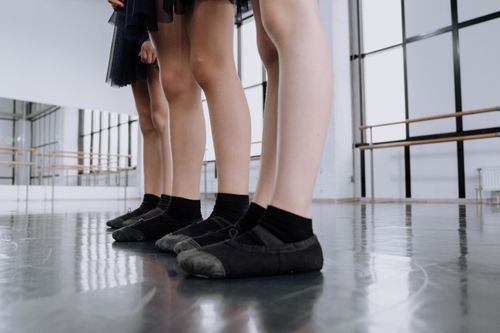 Free Young ballet students practicing in a bright, contemporary dance studio wearing black ballet flats. Stock Photo