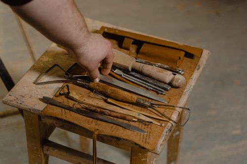 Free A close-up of artisan hand selecting tools on a wooden stool for woodwork. Stock Photo