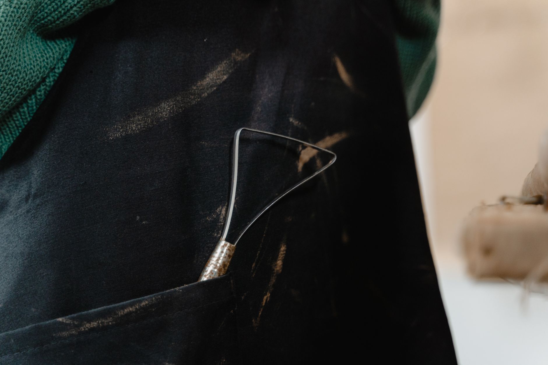 Detailed view of a sculptor's apron pocket holding a sculpting tool, showcasing an artistic workspace.