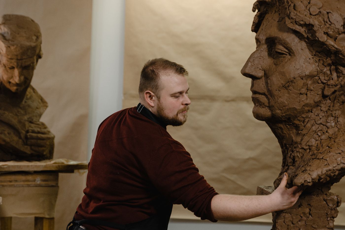 Sculpteur modelant un buste en terre dans son atelier