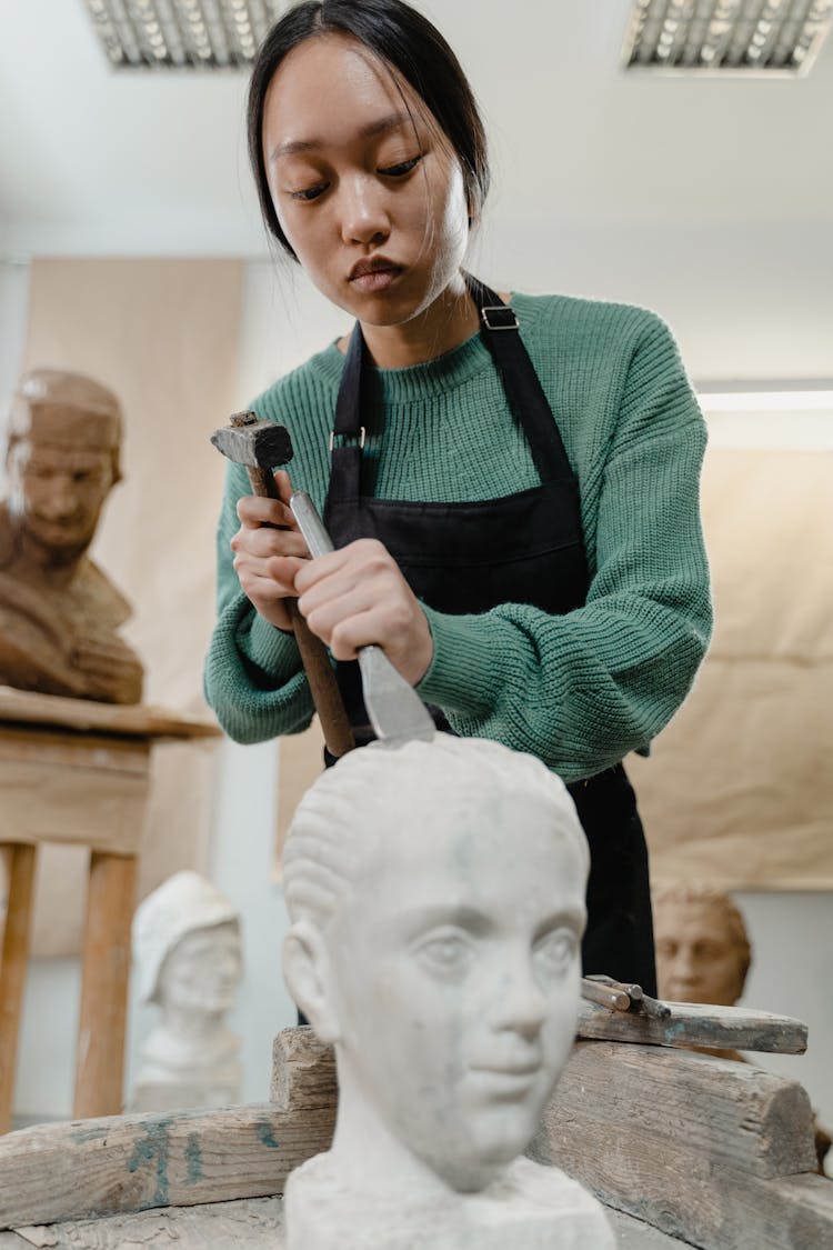 A Woman Using A Hammer A Chisel