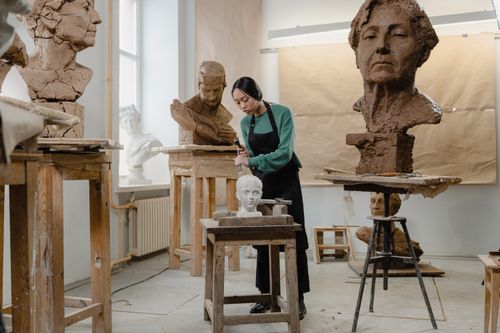 Free A focused female sculptor works on clay busts in an art studio. Stock Photo
