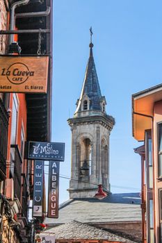 Explore the picturesque street view with a historic bell tower in a Spanish town.
