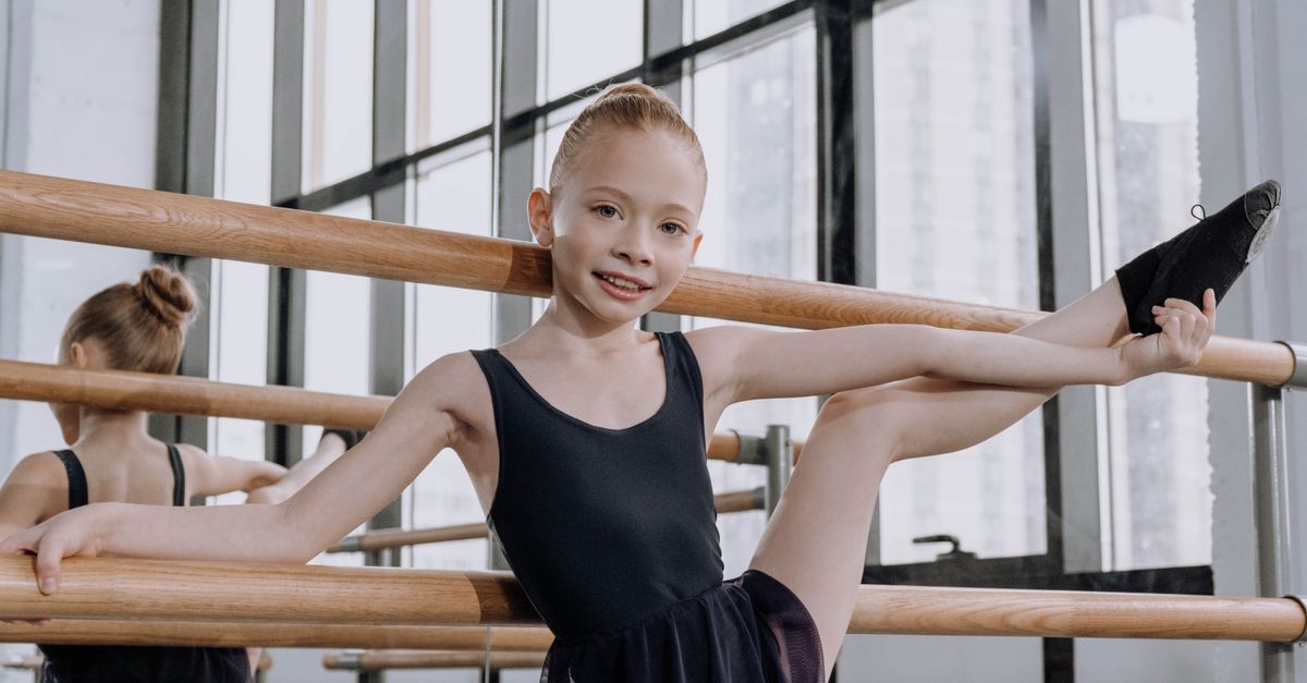 Young dancer stretching at the barre in a bright dance studio