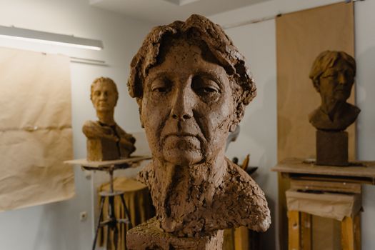 Detailed clay bust sculptures displayed in a creative art studio setting.