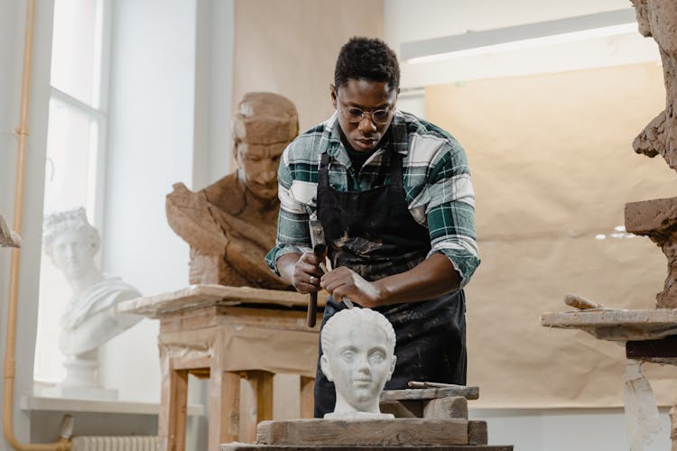 A Sculptor Using A Hammer And A Chisel