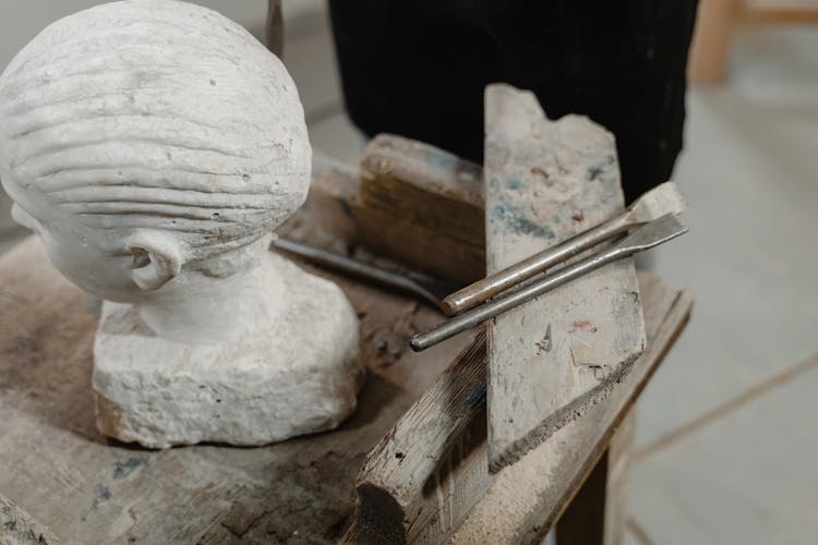 A Head Sculpture And Sculpting Tools On A Wooden Table