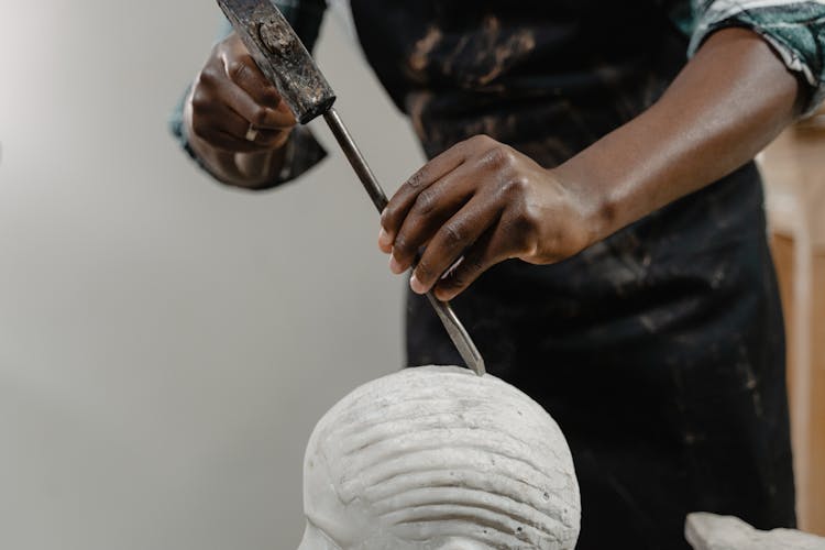 A Person Using A Hammer And A Chisel On A Sculpture