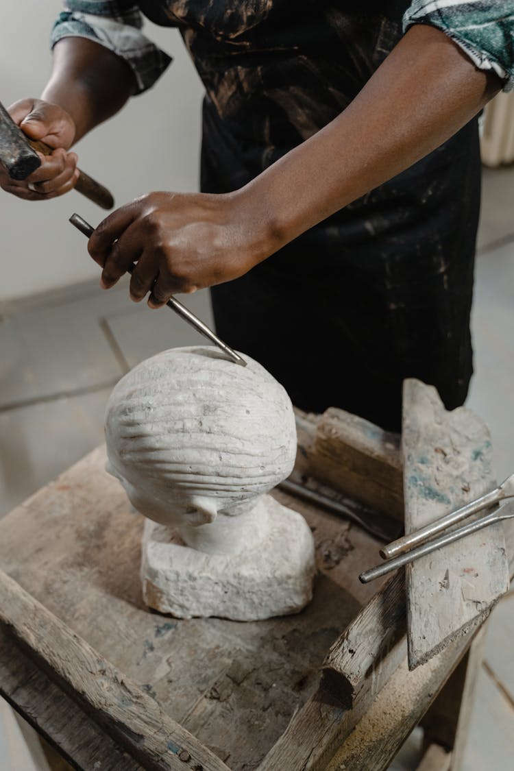 A Person Using A Hammer And A Chisel On A Sculpture