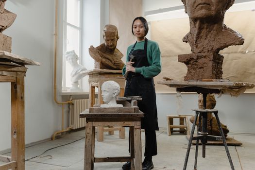 An artist in an art studio surrounded by sculptures, showcasing creativity and skill.