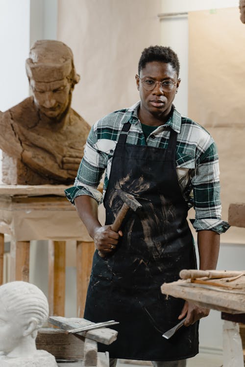 A Sculptor With Apron Holding A Hammer and Chisel 