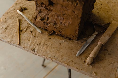 Free Detailed view of clay sculpture block with tools on a wooden table, showcasing craftsmanship. Stock Photo