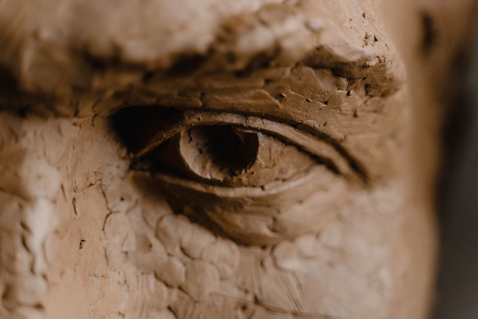 Intricate close-up of a clay sculpture focusing on the eye, showcasing detailed texture and craftsmanship.
