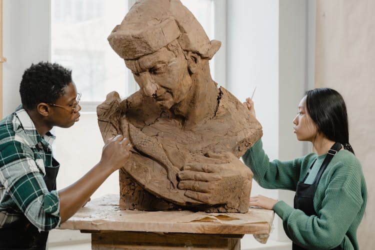 Sculptors Using Sculpting Tools On A Clay Statue