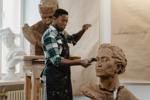 Artist sculpting a clay bust in a vibrant art studio, showcasing creativity.