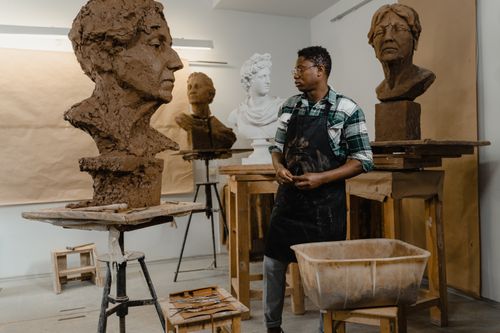 Free An artist in a studio working on detailed clay sculptures with artistic flair. Stock Photo
