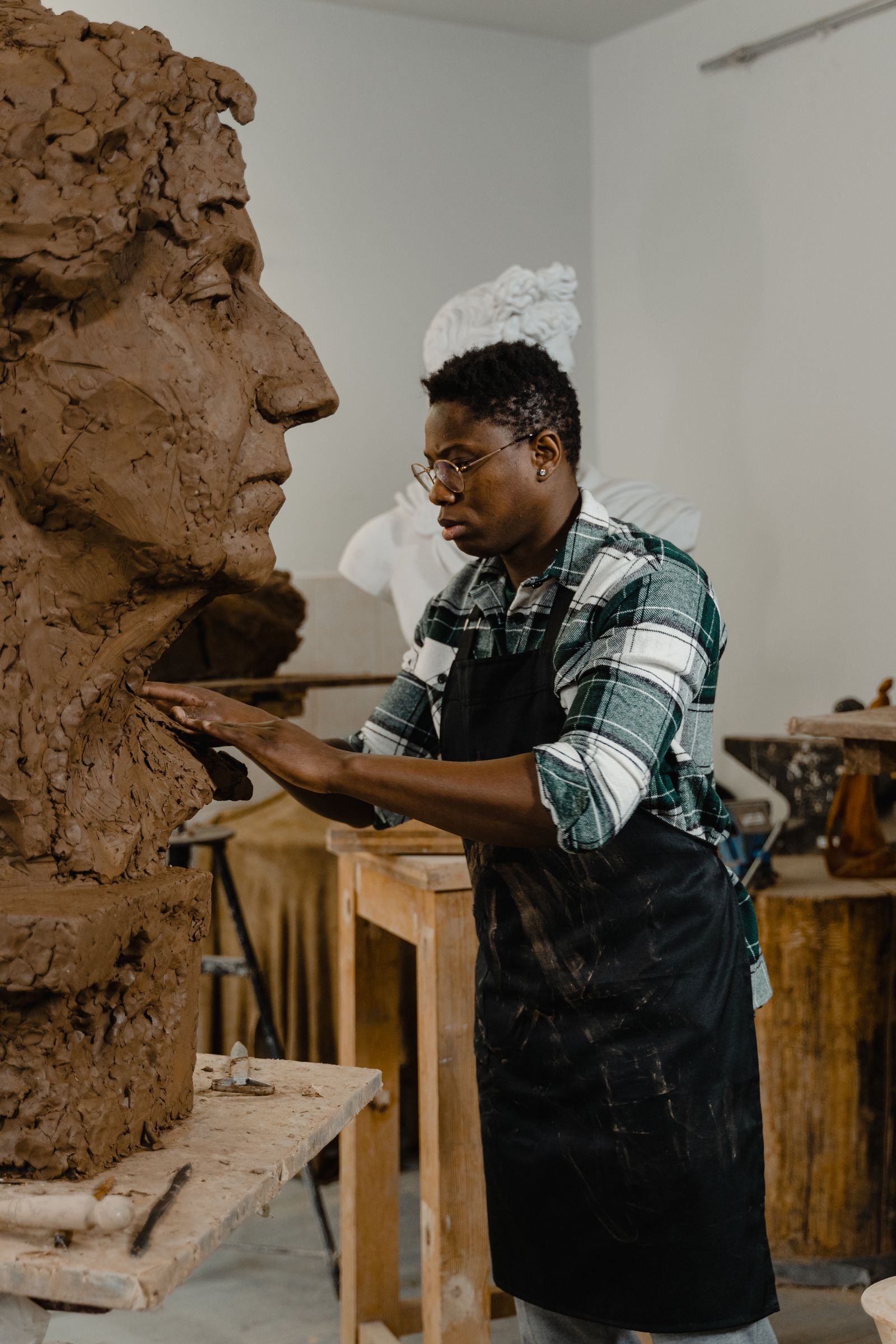 Sculptor modelling a large clay head in the studio