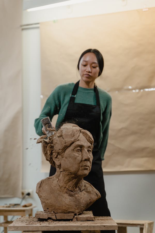 A Girl with Black Apron Destroying a Woman Head Bust