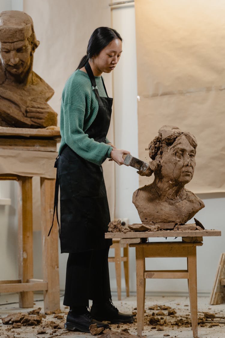 A Woman Hitting A Sculpture With A Hammer