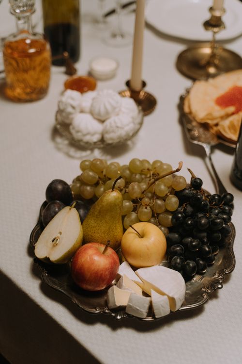 Free A beautifully arranged fruit and cheese platter featuring grapes, apples, pears and brie on a dining table setting. Stock Photo