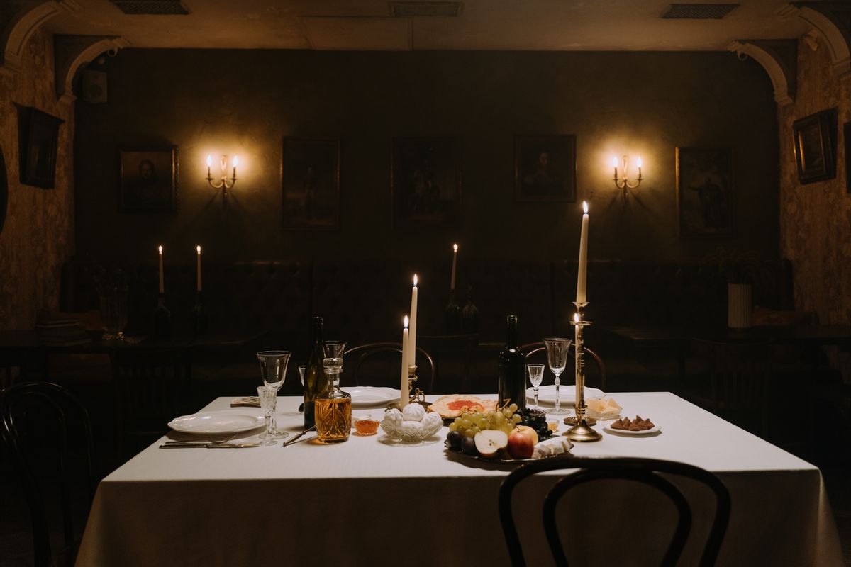 A candlelit Burgundian dining room, white cloth and old portraits