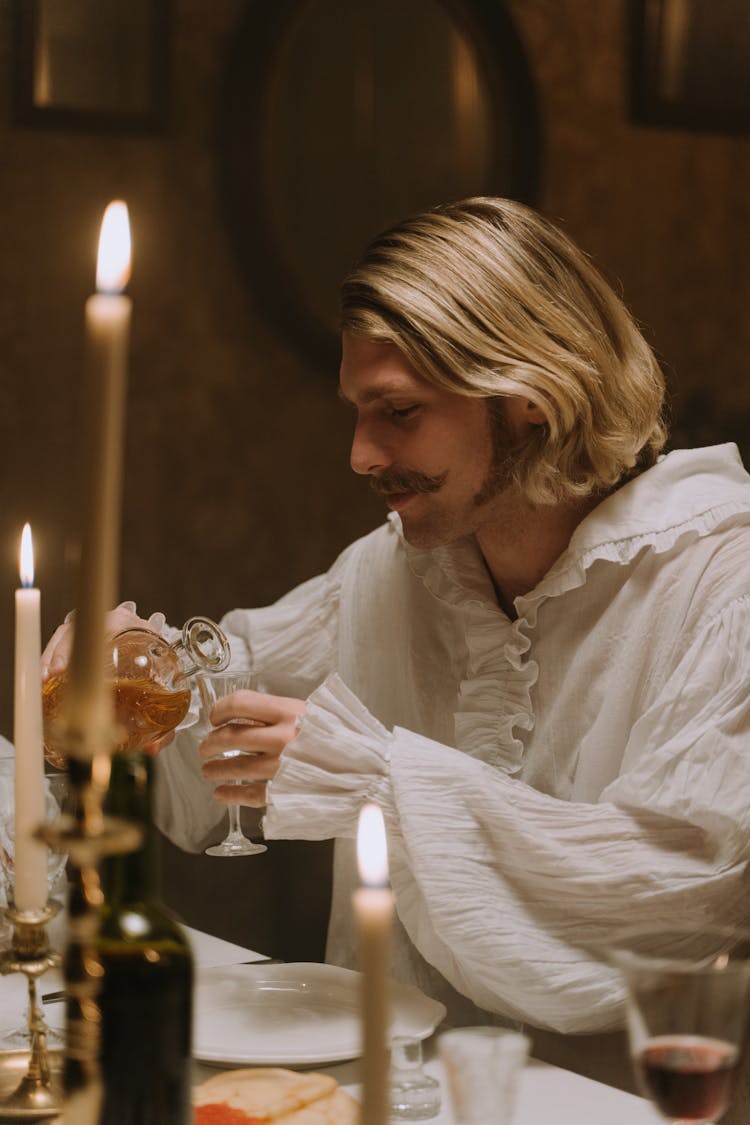 A Man In Medieval Pouring Wine In A Glass