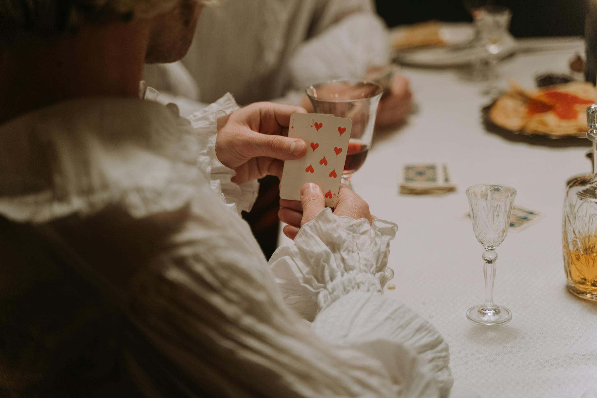 A group of adults engaged in a vintage card game, showcasing elegant attire and a cozy ambiance.