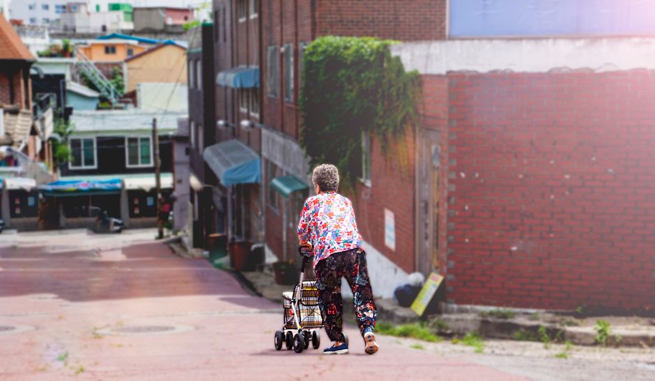 Senior woman with walker in colorful urban street, daytime.