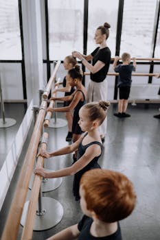 Children practicing ballet in a studio with their instructor guiding them.