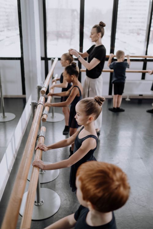 Free Children practicing ballet in a studio with their instructor guiding them. Stock Photo